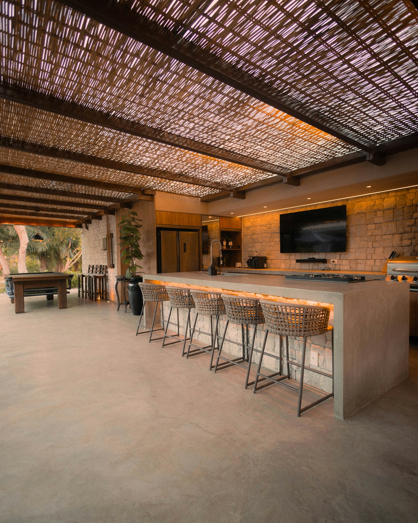 Modern outdoor kitchen with stone island and bar stools